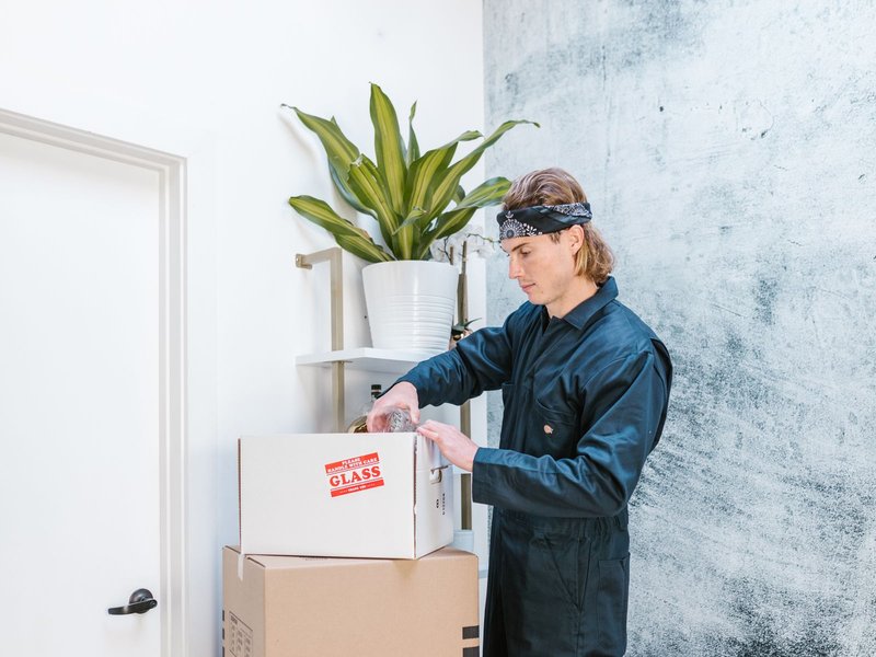 Umzugshelfer verpackt zerbrechliches Glas sorgfältig in einen Umzugskarton